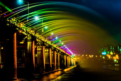 Illuminated bridge over water in city at night