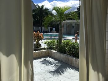 Swimming pool by palm trees against sky