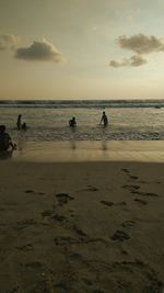 Silhouette people on beach against sky during sunset