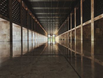 Perspective photo of the hallway of a mosque building reflected on the marble floor