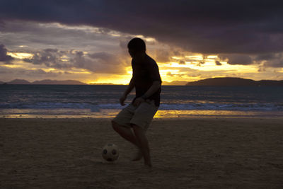 Man on beach against sky during sunset