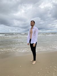 Full length of man standing on beach against sky