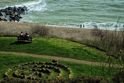 High angle view of people sitting on land by sea