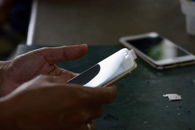 Cropped hands of person using mobile phone on table