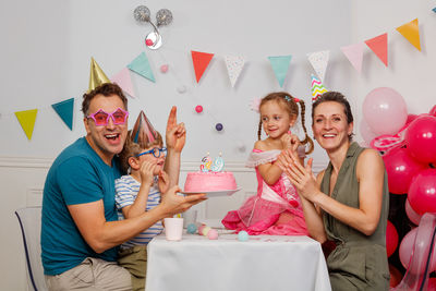 Portrait of smiling friends with arms raised sitting on table