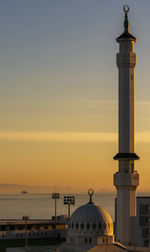 Tower by sea against sky during sunset