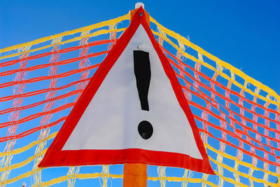 Low angle view of information sign on net against blue sky