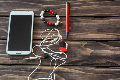 Close-up of mobile phone and ear phones on wooden table