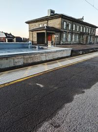 Empty road by building against sky in city