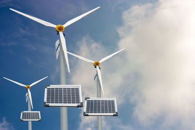 Low angle view of wind turbines against sky