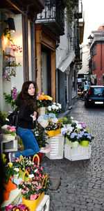 Woman standing by potted plants on street in city