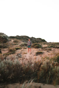 Woman standing on field against clear sky