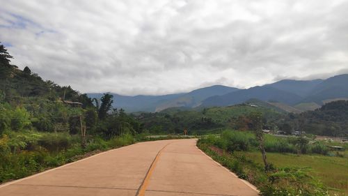 Road leading towards mountains against sky