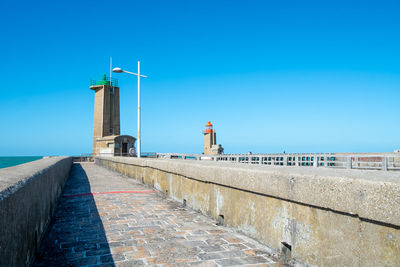 Footpath by lighthouse against clear blue sky