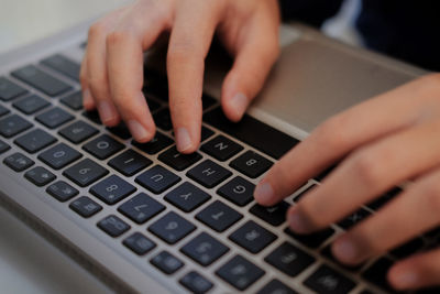 Cropped hands of person using laptop