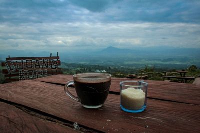 Coffee cup on table against mountains