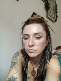 Portrait of young woman against wall at home