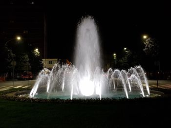 Illuminated fountain in city at night