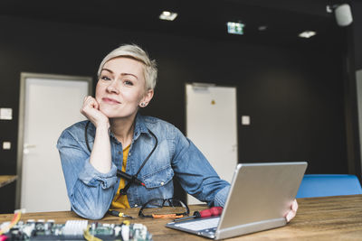 Portrait of smiling woman with laptop and computer equipment