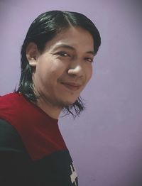Portrait of smiling young woman standing against wall