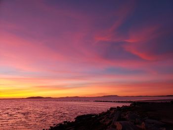 Scenic view of sea against dramatic sky during sunset