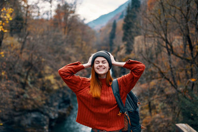 Portrait of smiling young woman standing in park during autumn