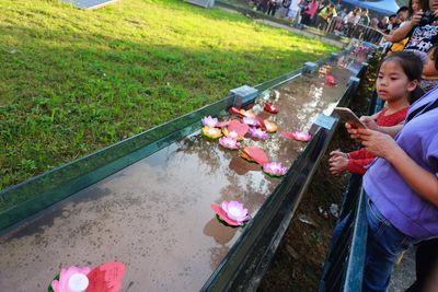 High angle view of women sitting on grass by water