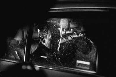 Man sitting in car seen through window at night