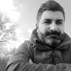 Portrait of man with arms crossed against trees