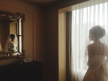 Bride standing by window at home