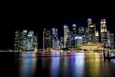 Illuminated cityscape by river at night