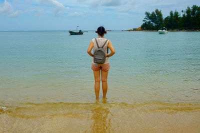 Rear view of young woman standing at beach