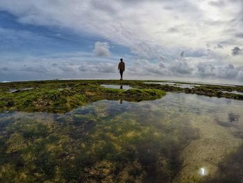 Man standing on shore against sky