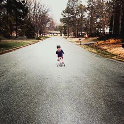 Rear view of girl riding on bicycle at road