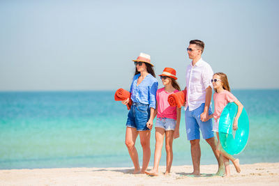 Full length of mother and daughter on beach against sky