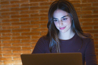 Young woman using laptop while sitting on table