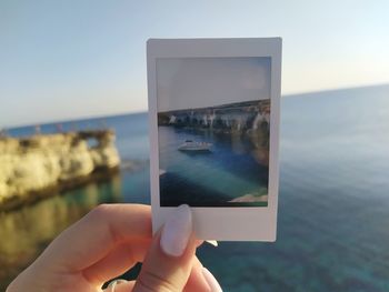 Midsection of person photographing sea against sky