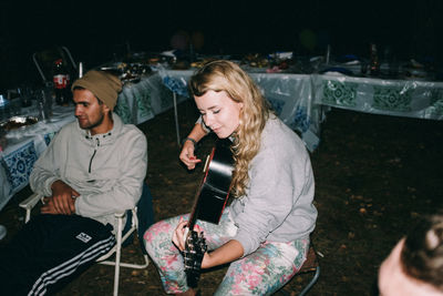 Young women sitting on wall at night