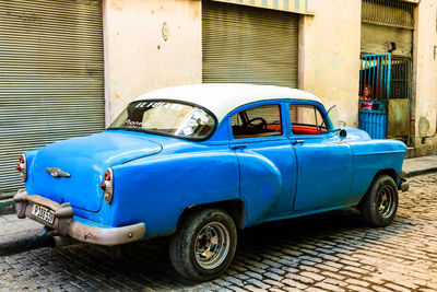 Old vintage car on street against buildings