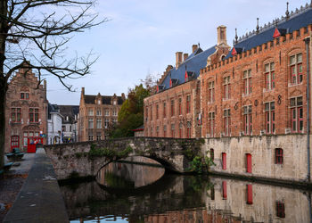 Canal amidst buildings against sky in brugge, belgium