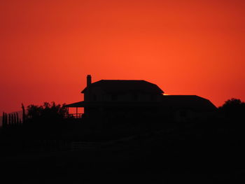 Silhouette house against orange sky