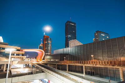 Low angle view of illuminated buildings against clear blue sky