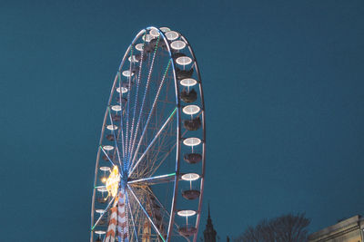 Low angle view of ferris wheel against blue sky