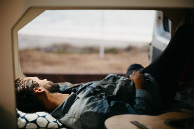 Man with guitar lying down on bed