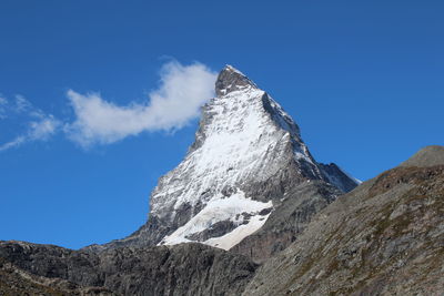 Low angle view of snowcapped mountain against blue sky