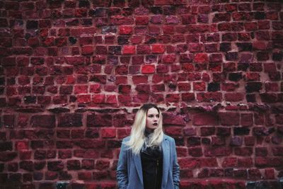 Portrait of cute girl against red brick wall