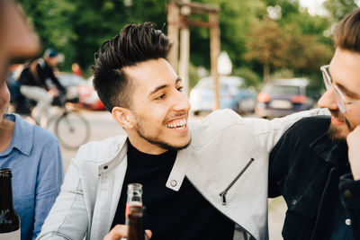 Young man looking at male friend while sitting at garden party