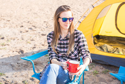 Young woman wearing sunglasses sitting outdoors