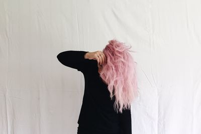 Woman with pink hair standing by window