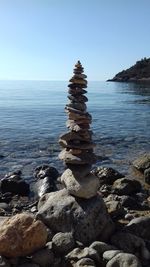 Stack of stones in sea against clear sky